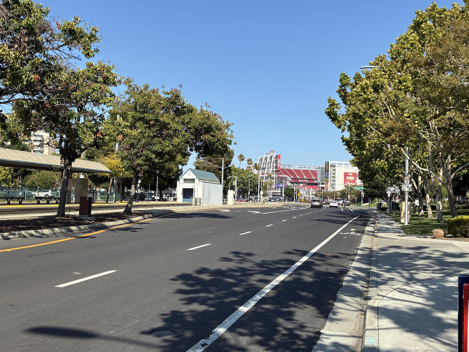 A wide, almost empty boulevard running toward the stadium, trees along both sides